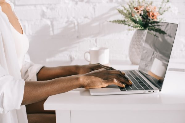 cropped view of african american woman using laptop in white kitchen